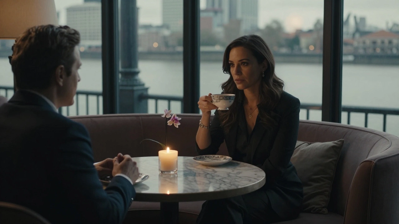 Two profiles sit across from each other in a softly lit lounge, sharing a quiet moment over tea.